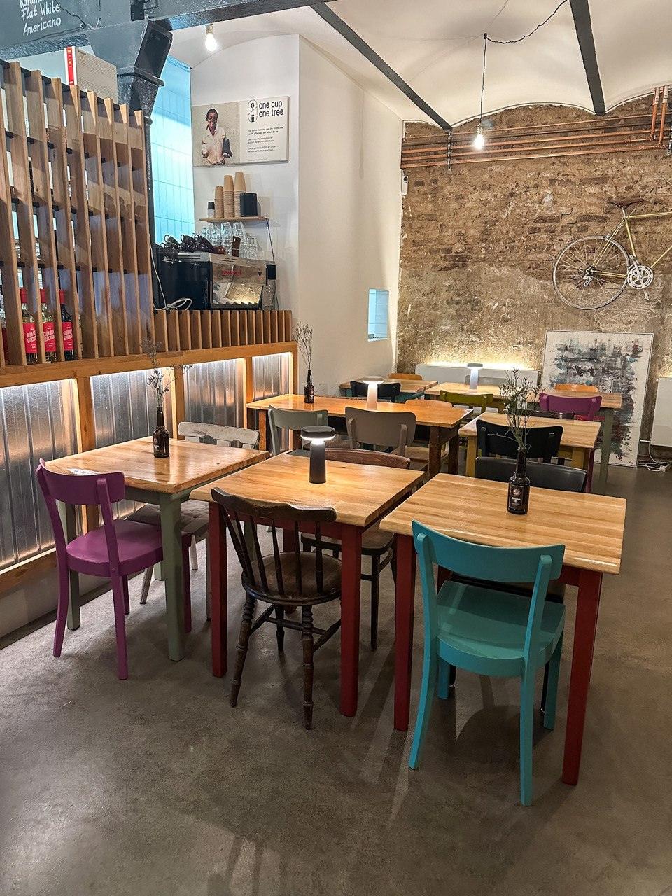 Gemütliches Café mit bunten Stühlen, Holztischen und Vintage-Deko in Düsseldorf-Gerresheim.
